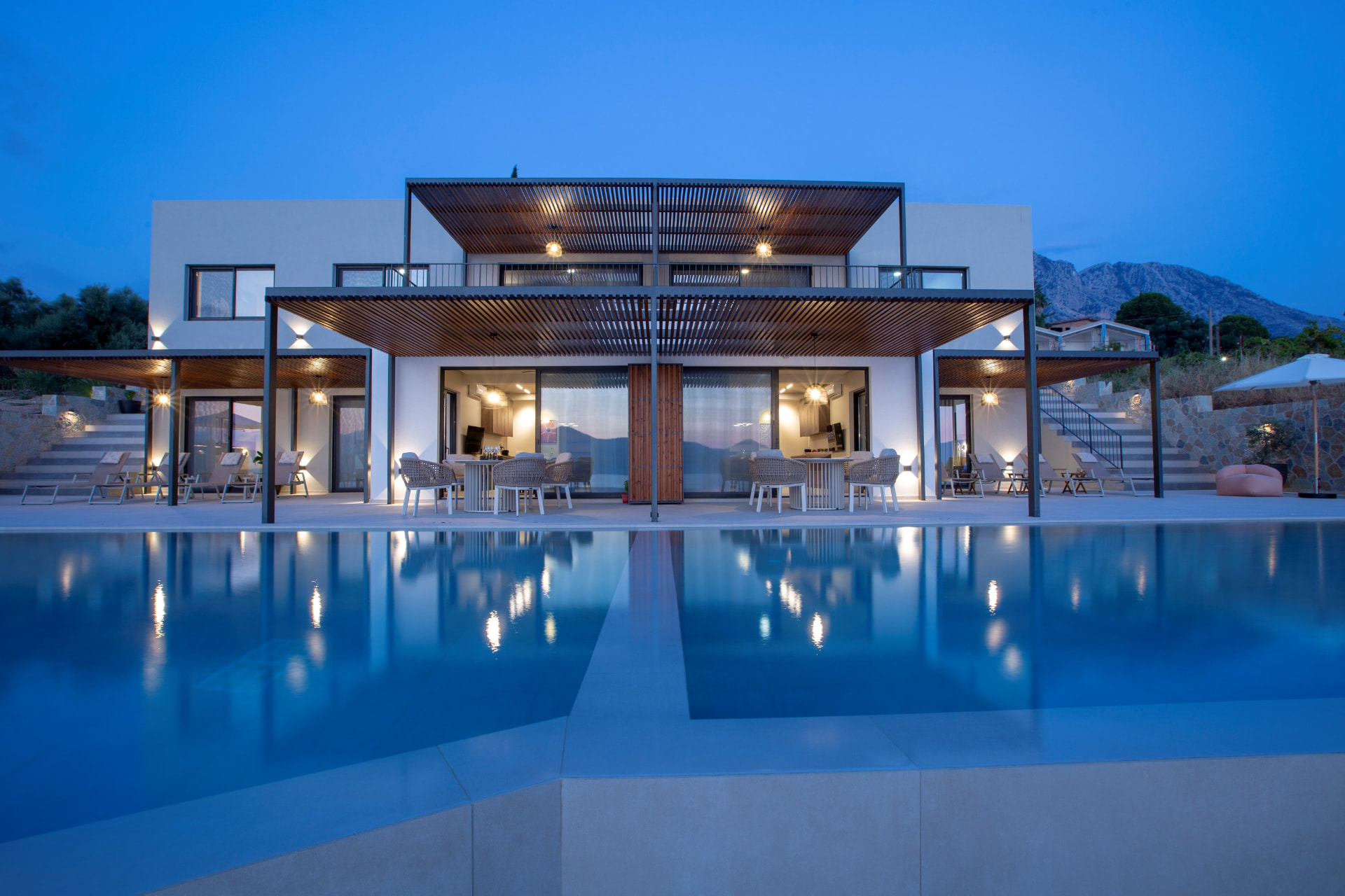 ZOE Sea View Villas illuminated at dusk with the pool reflecting the villa facade